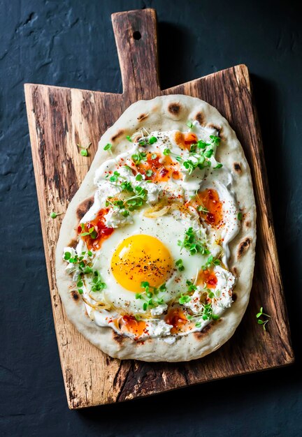 Focaccia per colazione turca con salsa di peperoncino e yogurt all'uovo fritto e formaggio