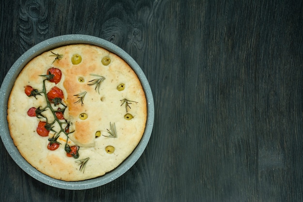 Focaccia tradizionale italiana con pomodori, olive e rosmarino. Focaccia al forno in una teglia. Cucina italiana . Spazio per il testo.