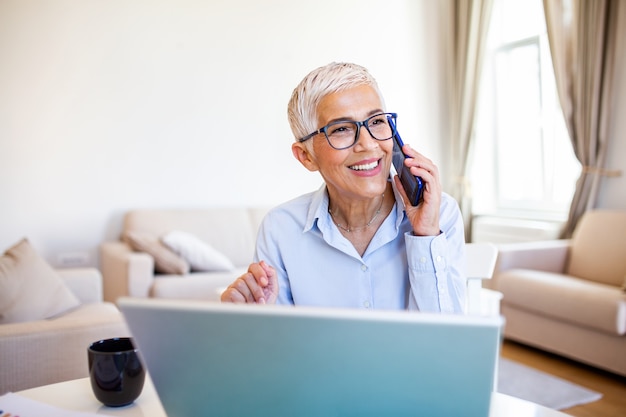 Focalizzato vecchia donna con i capelli bianchi a casa utilizzando il computer portatile