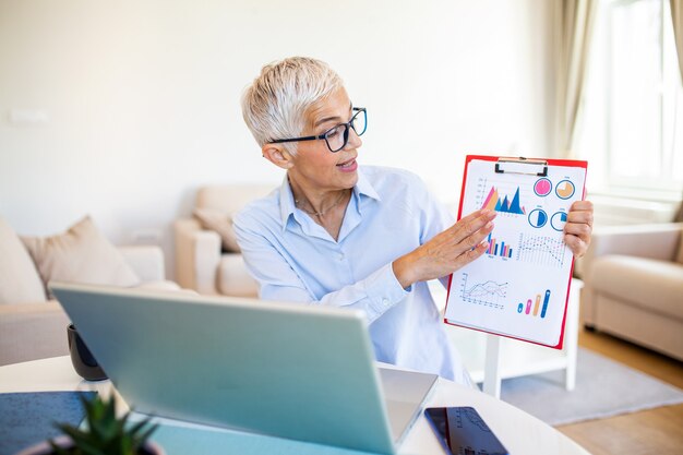 Focalizzato vecchia donna con i capelli bianchi a casa utilizzando il computer portatile