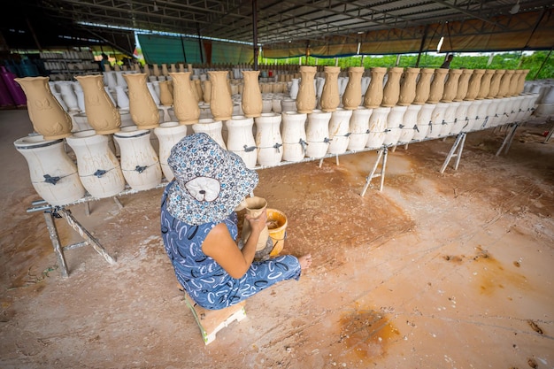 Focalizzazione donna che lavora nella fabbrica di ceramica Stack di piccole tazze in ceramica grezze su scaffale stampo di tazza in ceramika processo tradizionale di produzione di tazze ceramiche in fabbrica