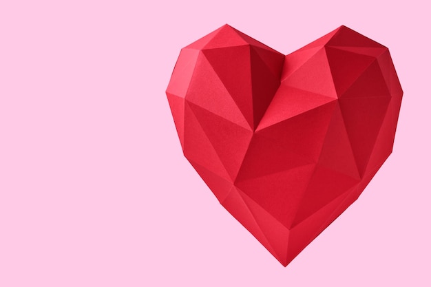 Focolare di carta rosso isolato su sfondo rosa. Cuore di carta poligonale rosso per San Valentino o qualsiasi altro biglietto d'invito Love. Vista dall'alto, copia dello spazio.