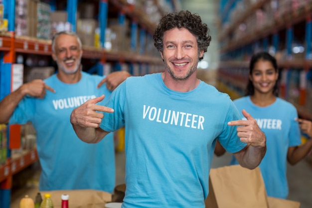 Focus di volontariato felice mostrando la sua maglietta davanti alla sua squadra