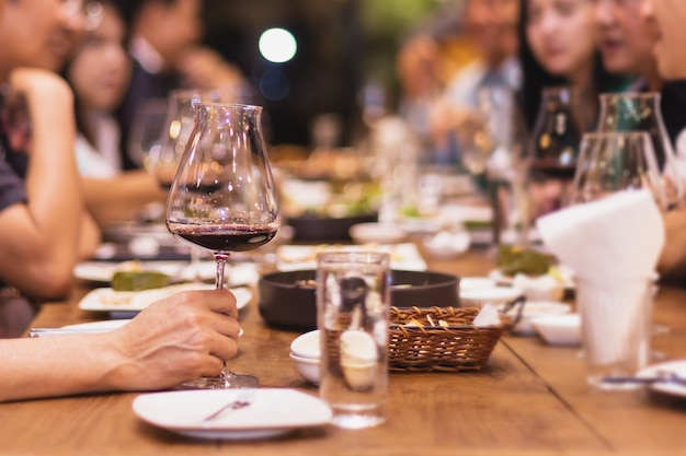 Focus group selezionato di amici che cenano al ristorante bevendo vino rosso al coperto