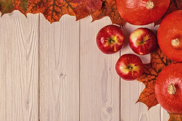 Fogli di autunno con le zucche su una tabella di legno