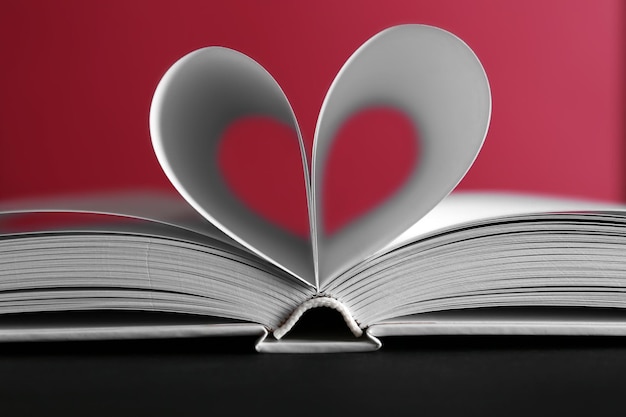 Fogli di libro curvati a forma di cuore su sfondo rosa