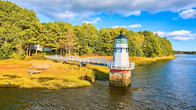 Fogliame autunnale sulla costa con piccolo faro nel Maine e passerella