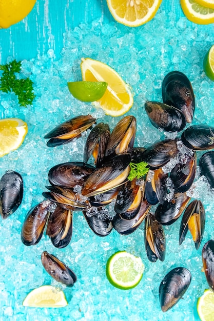 foglie crude aperte di cozze di fiume di mare, ghiaccio marino blu sul ghiaccio, fette di limone e lime vengono affettate