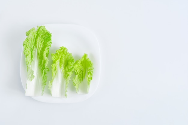 Foglie dell'insalata sul piatto bianco sulla tavola bianca. Concetto di dieta