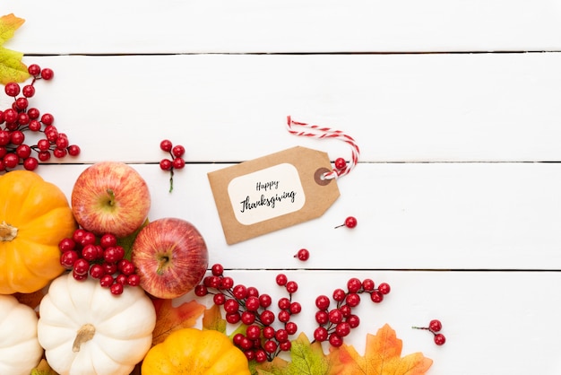 Foglie di acero di autunno con la zucca e le bacche rosse su fondo di legno.