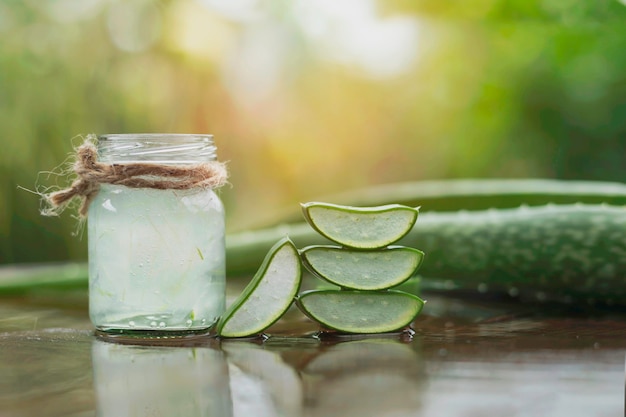 Foglie di aloe vera e un bicchiere d'acqua posate sul pavimento di legno