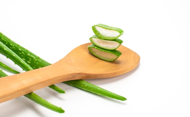 Foglie di aloe verde fresco a fette in cucchiaio di legno isolato su sfondo bianco. Concetto di cura della pelle, spa di salute e bellezza.