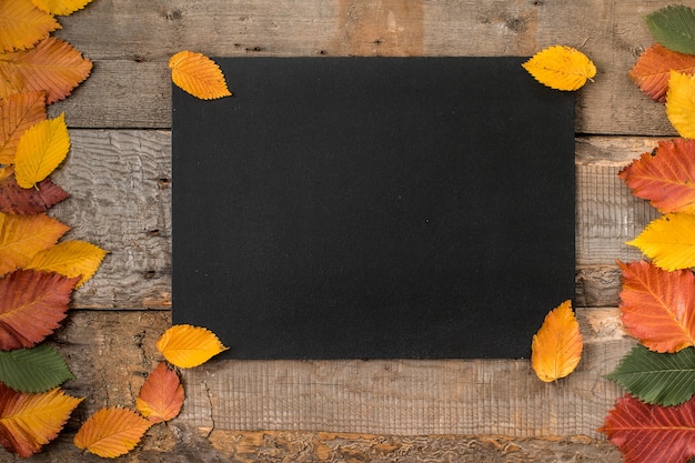 Foglie di autunno con una lavagna su un tavolo di legno