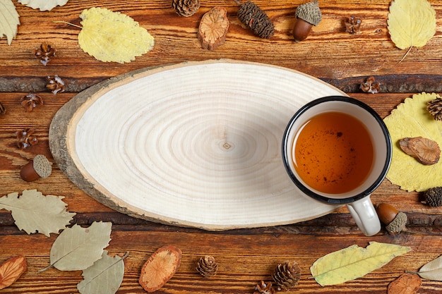 Foglie di autunno gialle e un bicchiere di tè su un vecchio fondo di legno scuro con uno spazio in bianco per testo