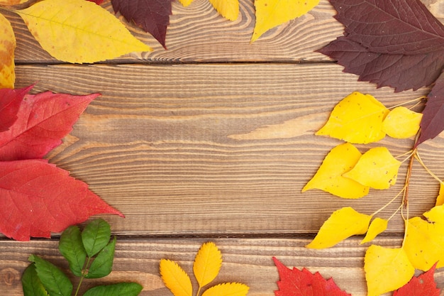 Foglie di autunno su sfondo di legno con spazio di copia