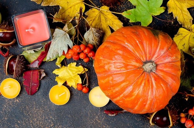 Foglie di autunno, zucca, castagne, candele su un buio