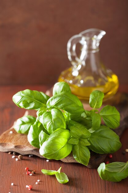 Foglie di basilico fresco erba e olio d'oliva su fondo in legno