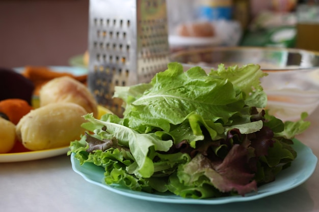 Foglie di insalata verde fresca in un piatto sul tavolo mentre si cucina in cucina