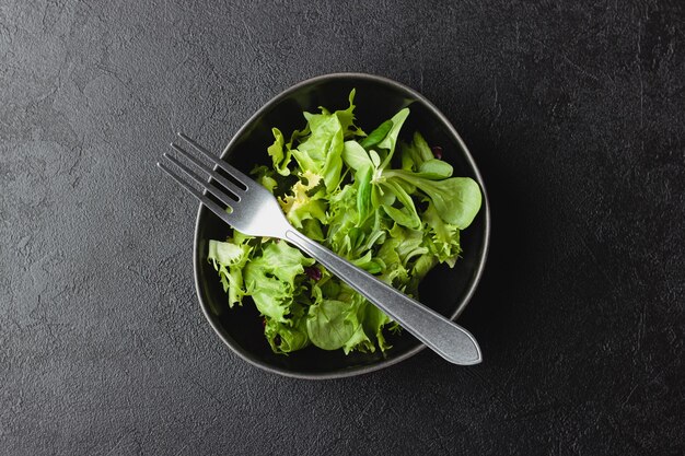 Foglie di insalata verde in una ciotola sul tavolo nero