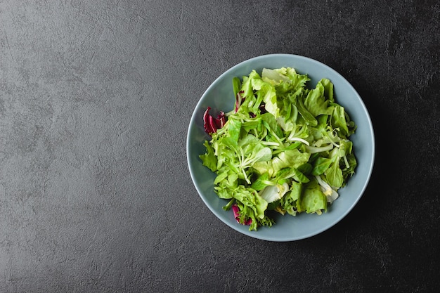 Foglie di insalata verde in una ciotola sul tavolo nero