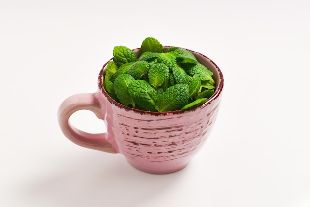 Foglie di menta in una tazza isolata su sfondo bianco.