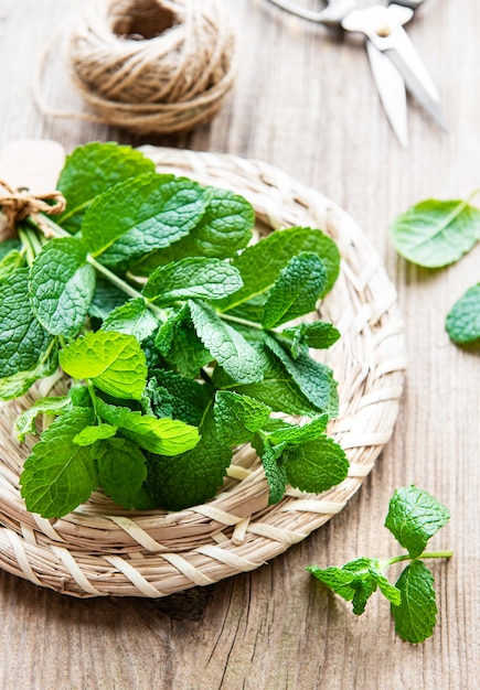 Foglie di menta verde fresca nel piatto sulla vecchia tavola di legno