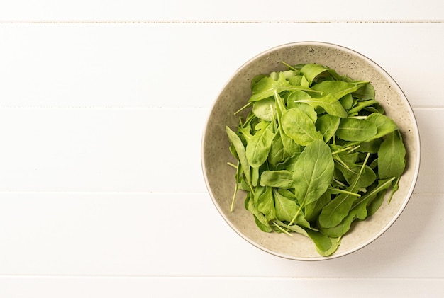 Foglie di rucola fresca nella vista dall'alto della ciotola bianca