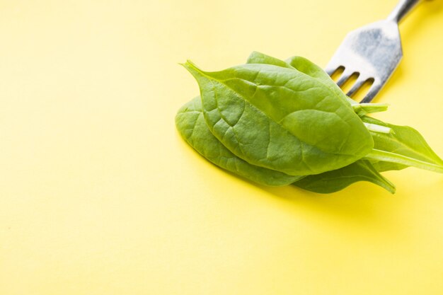 Foglie di spinaci fresche infilate su una forchetta. Concetto di mangiare sano