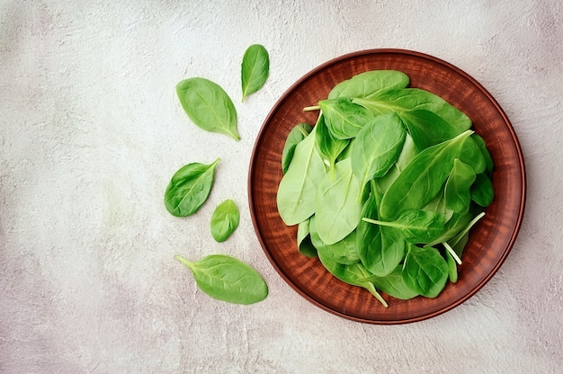 Foglie di spinaci nel piatto sul tavolo di cemento.