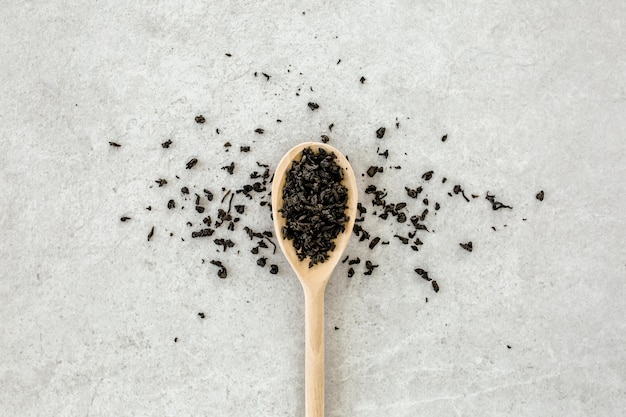 Foglie di tè secche su sfondo grigio piatto