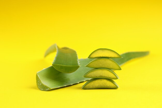 Foglie e fette di aloe vera su sfondo giallo