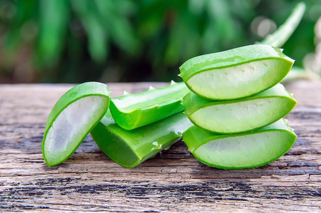 Foglie e fette fresche di vera dell'aloe sulla tavola di legno.