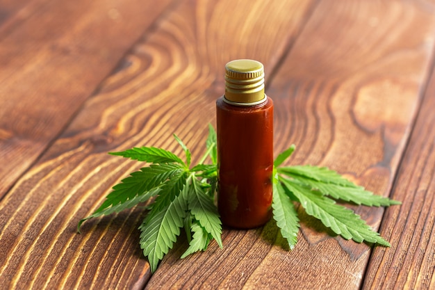 Foglie ed olio di cannabis su fondo di legno