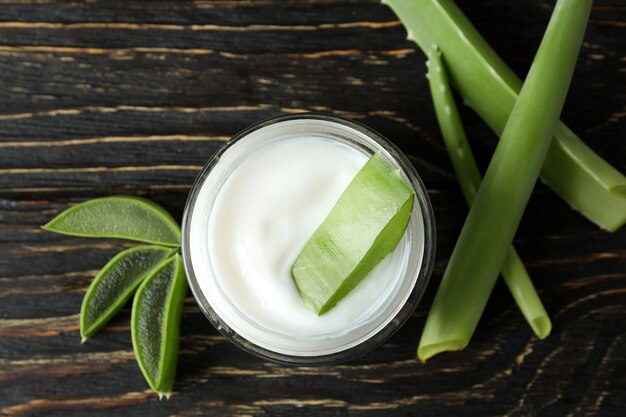 Foglie, fette e crema di aloe vera su fondo di legno