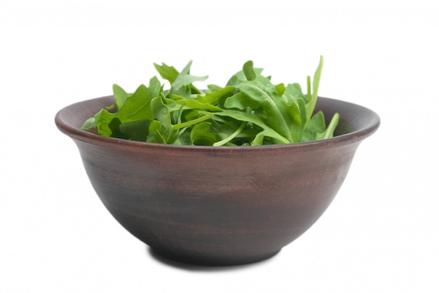 Foglie fresche di rucola in ciotola di ceramica marrone isolato