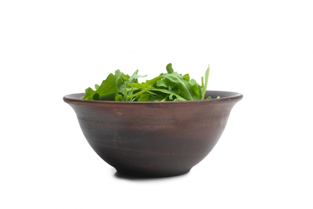 Foglie fresche di rucola in ciotola di ceramica marrone isolato.