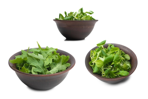 Foglie fresche di rucola in ciotola marrone ceramica isolata