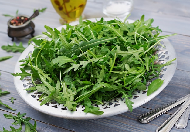 Foglie fresche di rucola in una ciotola su un fondo di legno leggero