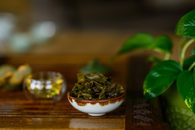 Foglie preparate di tè cinese oolong in una tazza su una tavola di legno del tè. Cerimonia del tè.