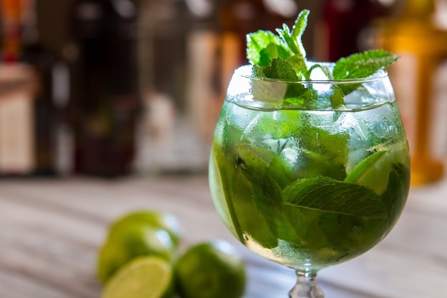 Foglie verdi nel bicchiere da cocktail. Bevanda con ghiaccio. Goditi una bevanda fresca. Hugo con menta e lime.