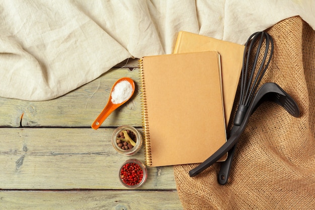 Foglio bianco di blocco note aperto e utensili da cucina sul tavolo con tovaglia