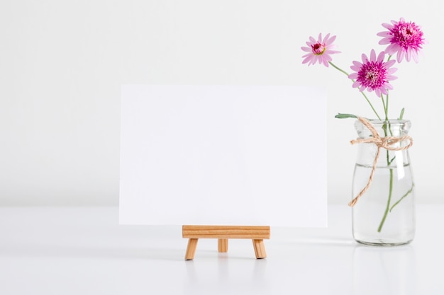 Foglio di carta bianco e fiori rosa in vaso