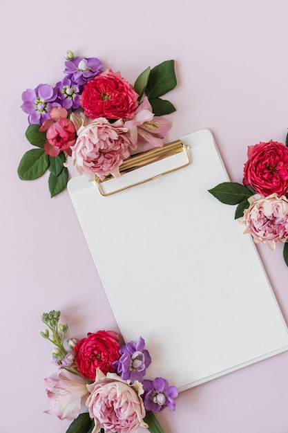 Foglio di carta bianco per appunti per tablet con spazio per la copia mockup fiori di rosa su sfondo rosa neutro del tavolo Modello di business minimo con vista dall'alto piatto