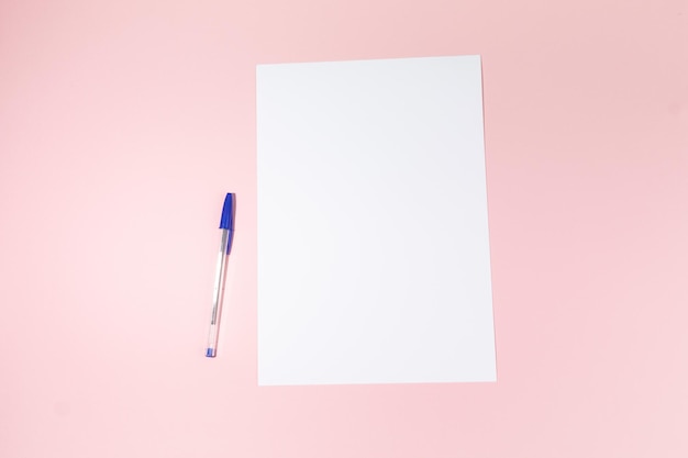 Foglio di carta bianco vuoto e una penna su sfondo rosa mockup