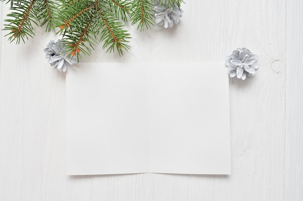 Foglio di carta bianco vuoto su uno sfondo di Natale bianco di rami di abete e coni. Lettera a Babbo Natale