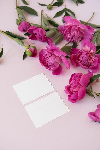 Foglio di carta di branding vuoto con spazio di copia mockup ed eleganti fiori di peonie su sfondo rosa Composizione di fiori estetici