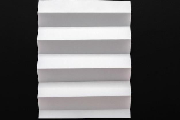 Foglio di carta piegato bianco su sfondo nero. Sfondo astratto, arte, concetto di origami, spazio di copia