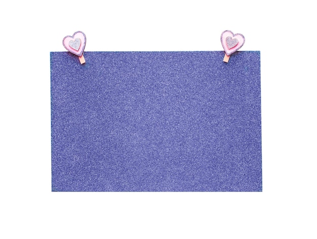 Foglio di carta viola glitter con mollette a forma di cuore rosa isolato su priorità bassa bianca