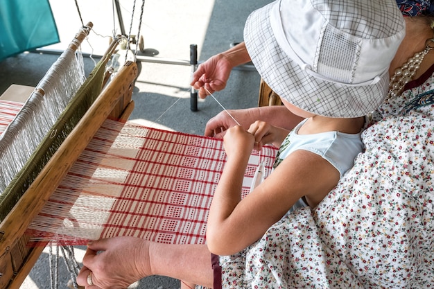 Folk Art Festival Un tessitore insegna a un bambino come fare il tessuto su un telaio a mano