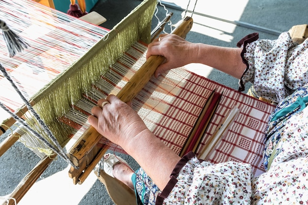 Folk Art Festival Una donna tessitrice realizza il tessuto su un vecchio telaio a mano Prodotti tessuti a mano